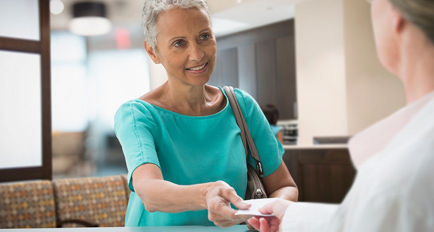 boomer woman handing over supplemental health insurance card