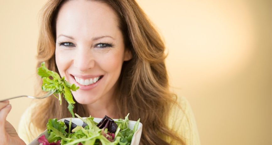 woman eating green salad with cancer fighting foods