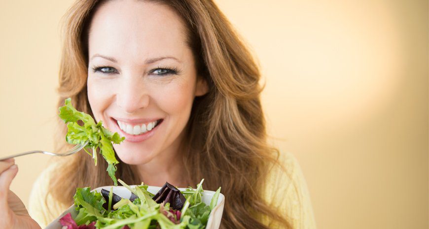 woman eating green salad with cancer fighting foods