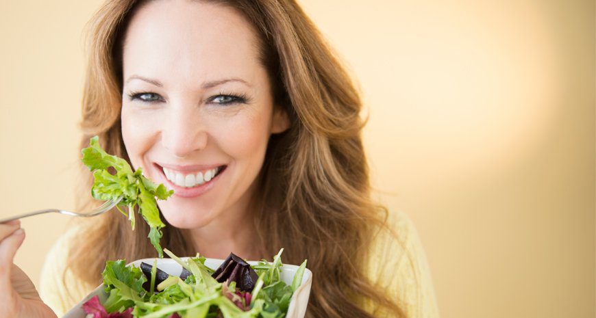 mujer comiendo ensalada verde con alimentos que combaten el cáncer