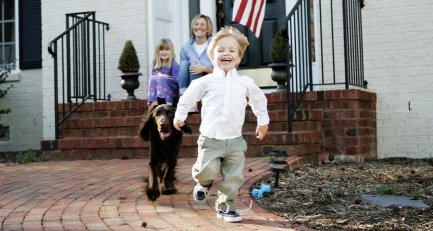 Little boy running in dress clothes ahead of his dog