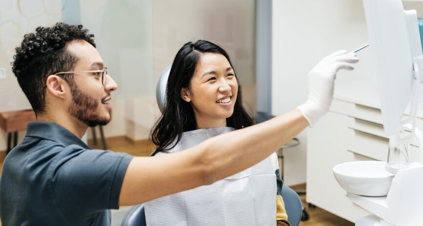 Dentist consulting with woman smiling patient on X-ray scans