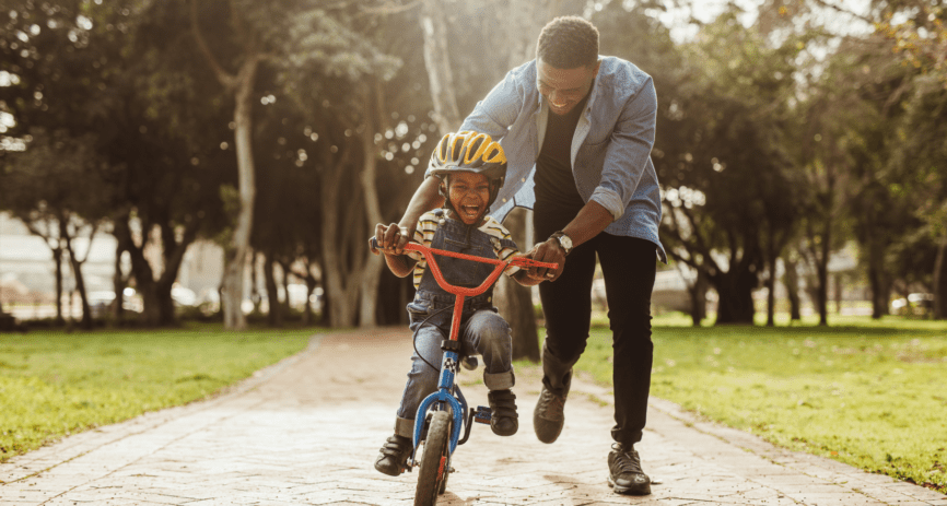 Child riding bike with parent's help