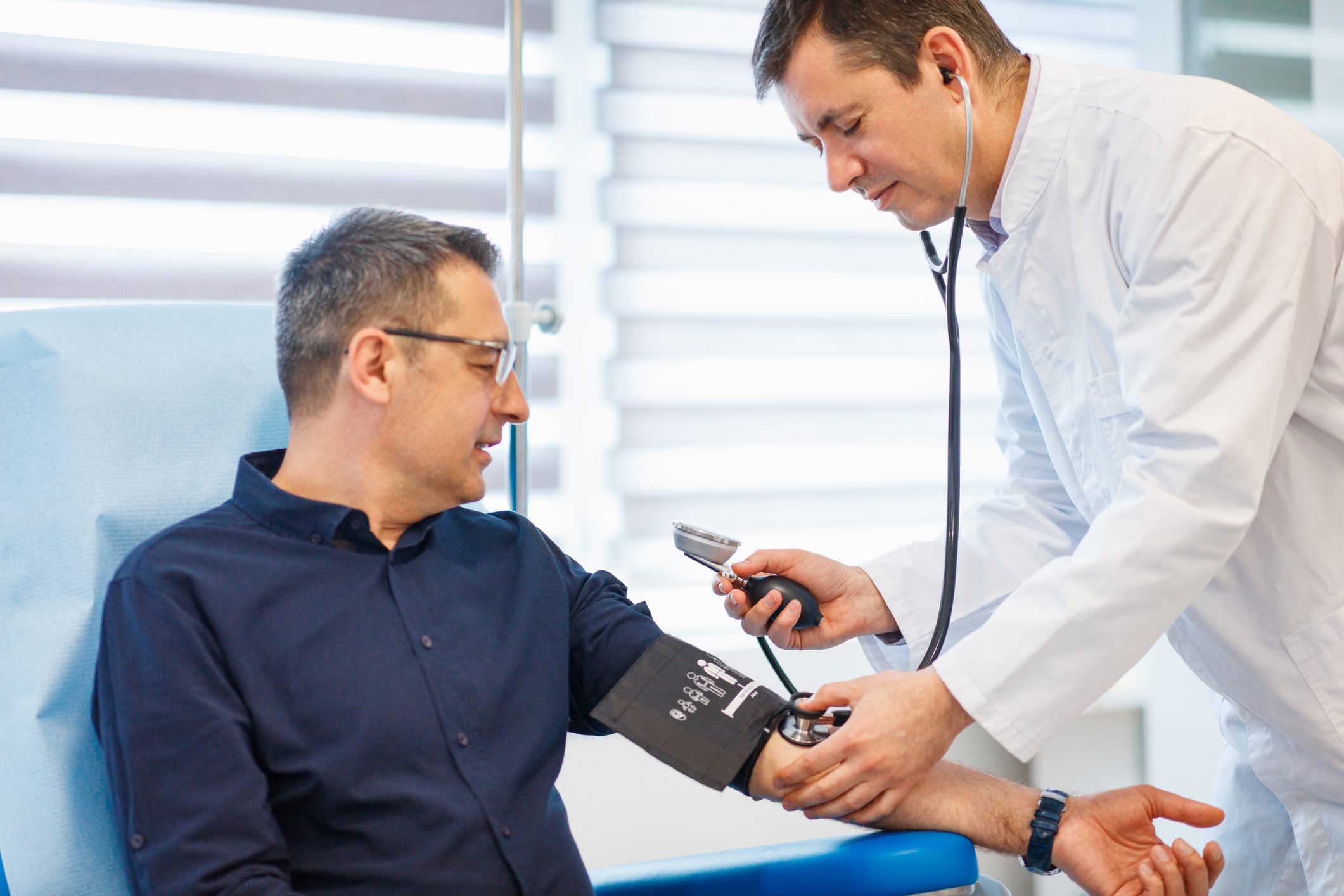 Doctor checking blood pressure of a mature male patient.