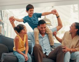 Young family on their sofa and the dad has the son on his shoulders.