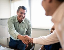 Coworkers greeting and doing a handshake at work.