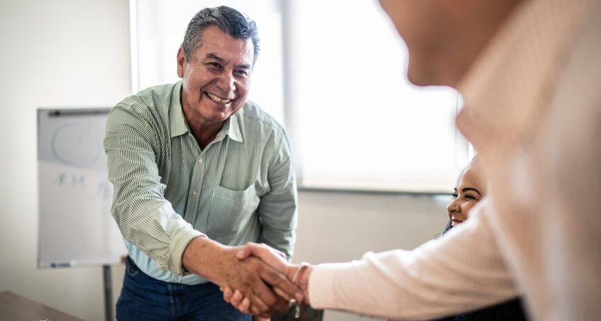 Coworkers greeting and doing a handshake at work.