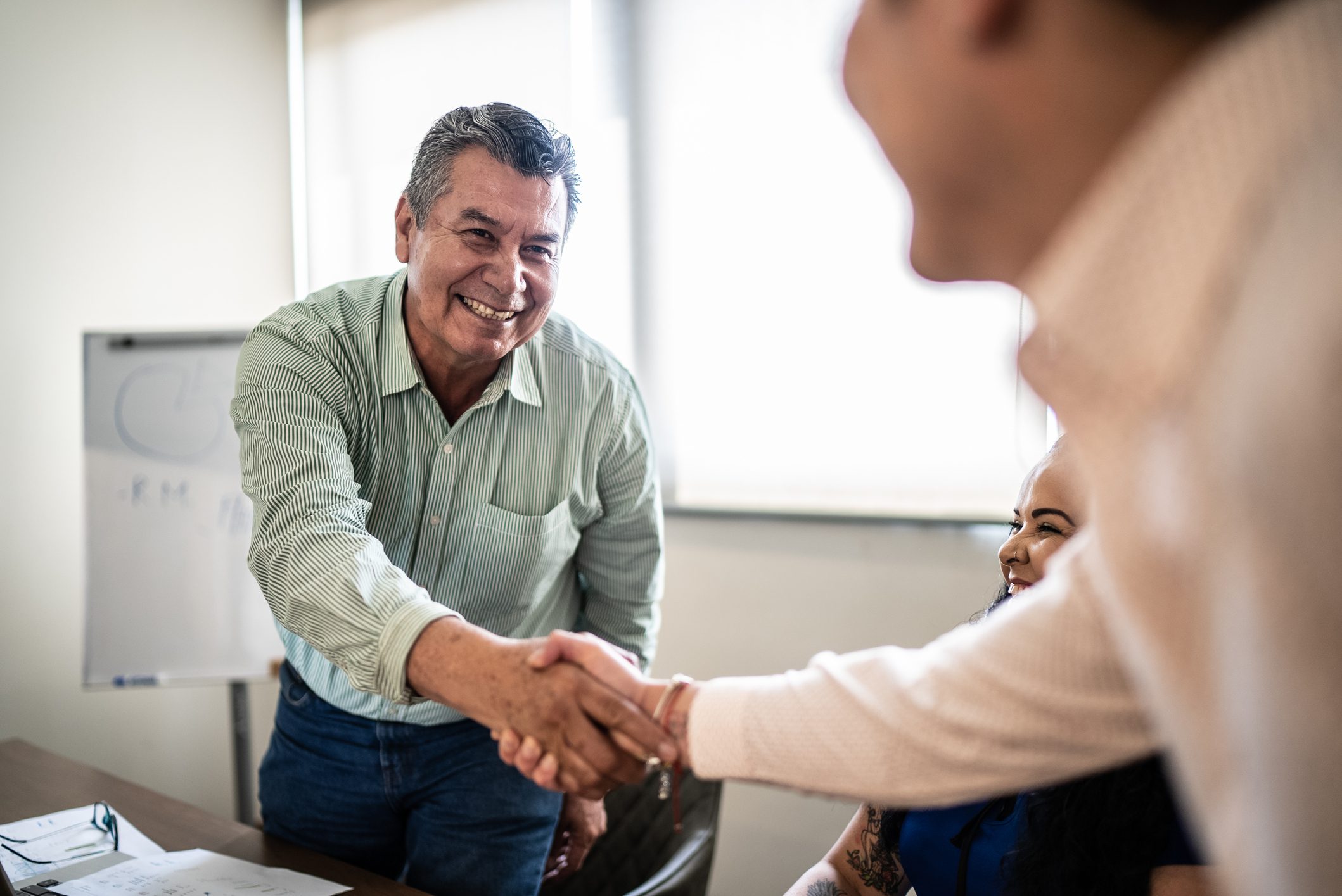 Coworkers greeting and doing a handshake at work.