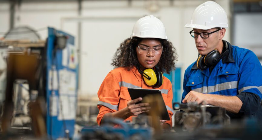 Two engineers work on a manufacturing floor.