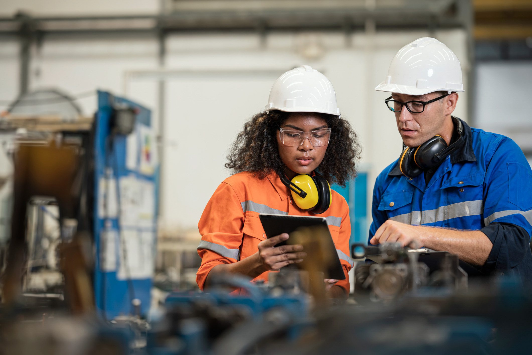 Two engineers work on a manufacturing floor.